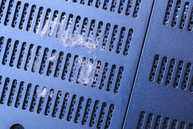 A close-up photo of a gaming console's ventilation grill completely clogged with dust, emphasizing the importance of regular cleaning.